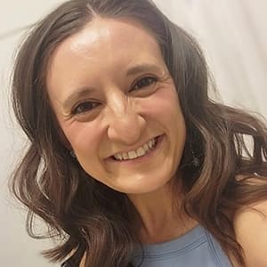 Woman with dark hair smiles with her teeth.