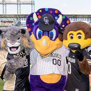 Lynx, dinosaur, and buffalo mascots stand together.