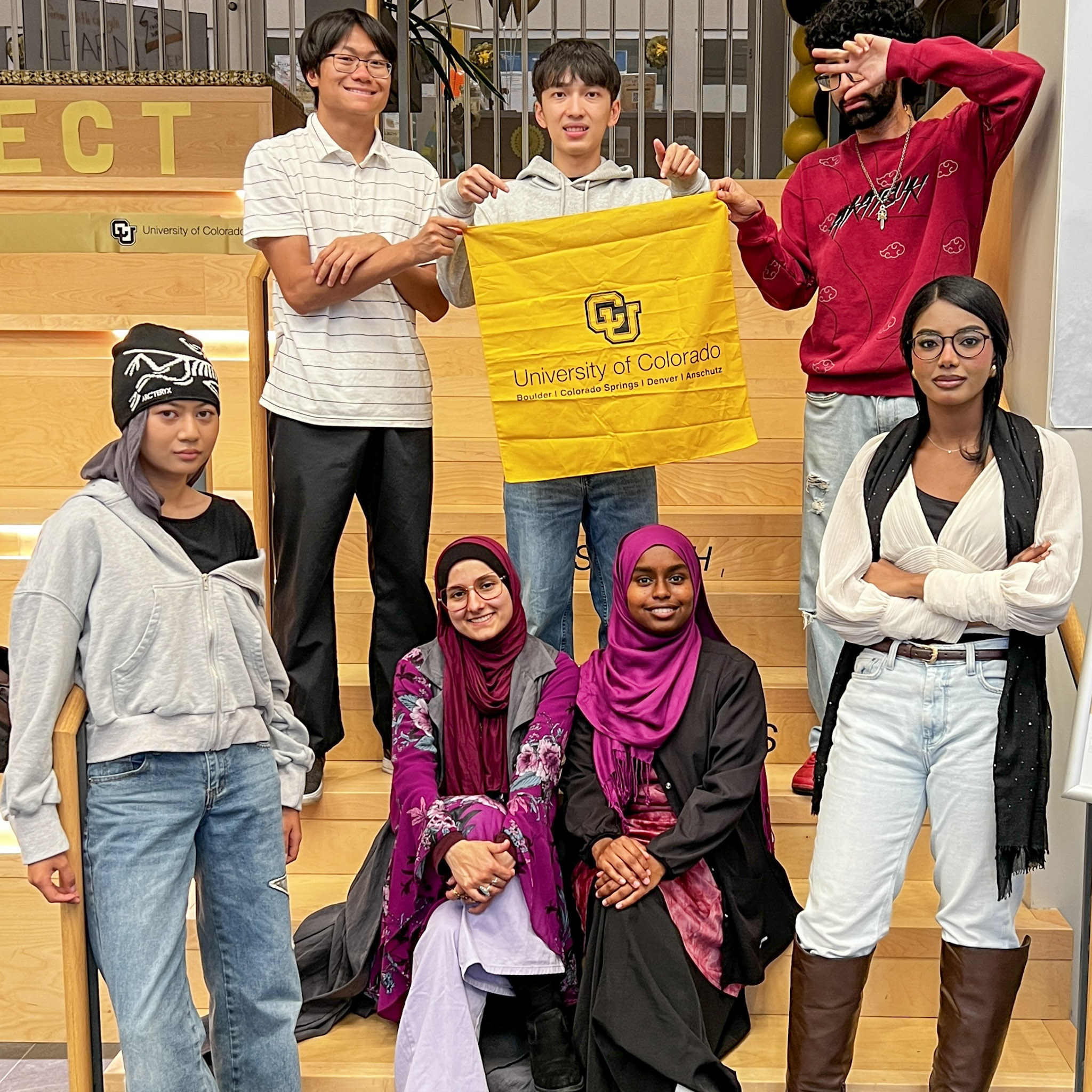 Six students pose together in LynxConnect, holding a University of Colorado flag.