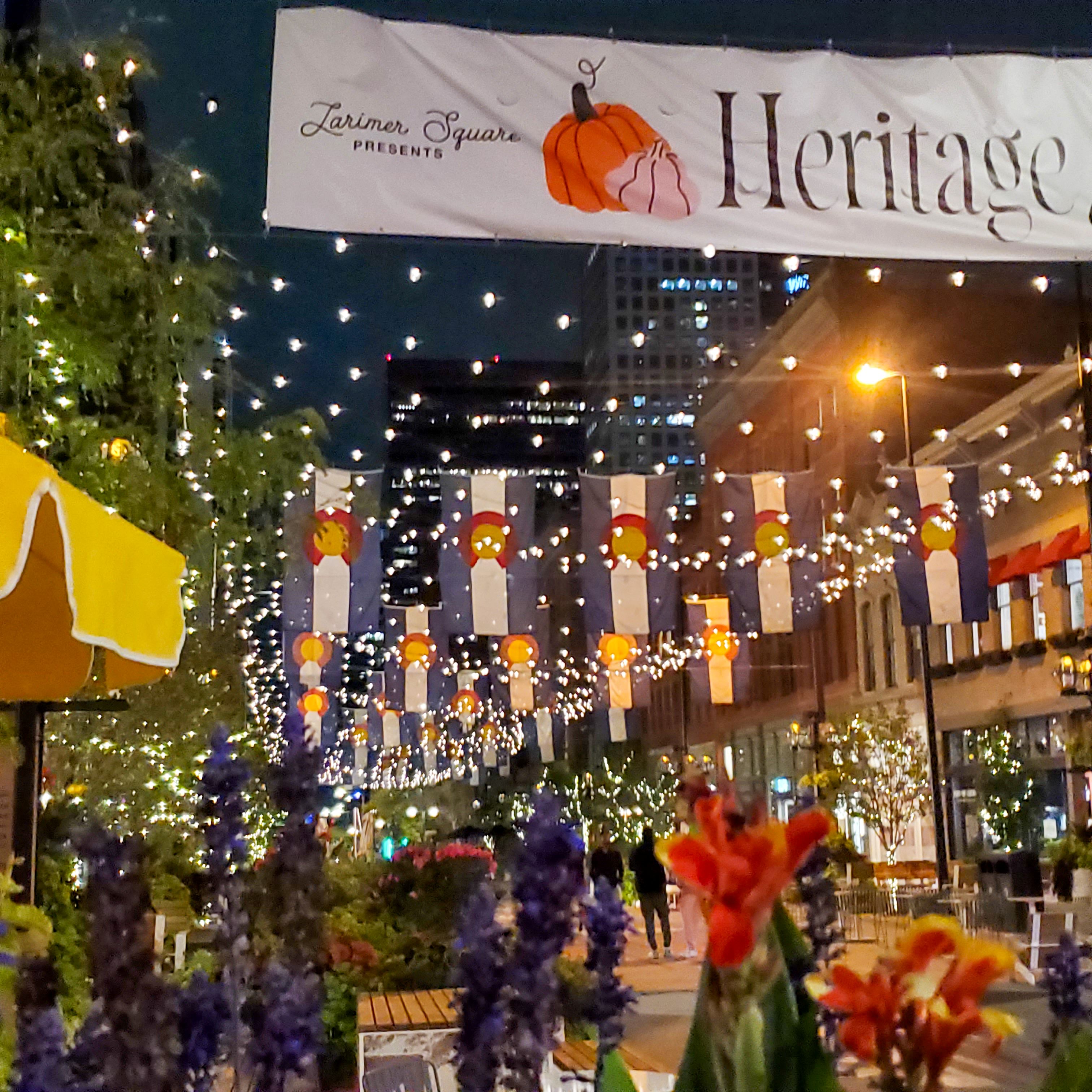 Evening view of Larimer Square in downtown Denver, illuminated by string lights and decorated with Colorado flags, flowers, and storefronts