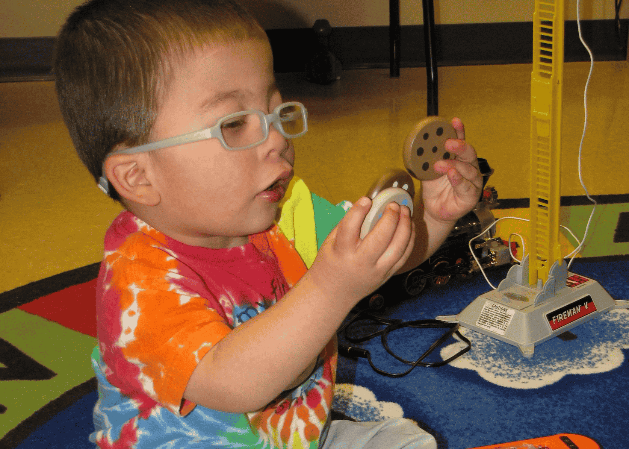A toddler with glasses looks close at toy blocks