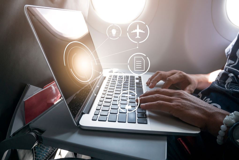 Image of a person working on a laptop while on a plane.